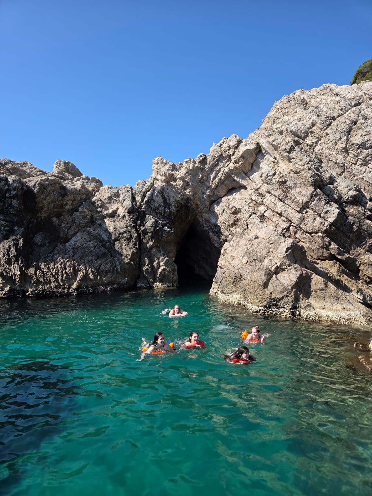 people swimming in clear turquoise water Dubrovnik Blue cave coastline boat tour Adriatic sea Croatia