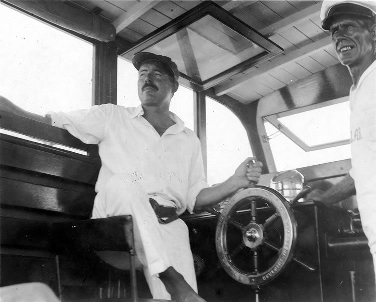 Ernest Hemingway at the wheel of his boat, Pilar, with Carlos Gutierrez