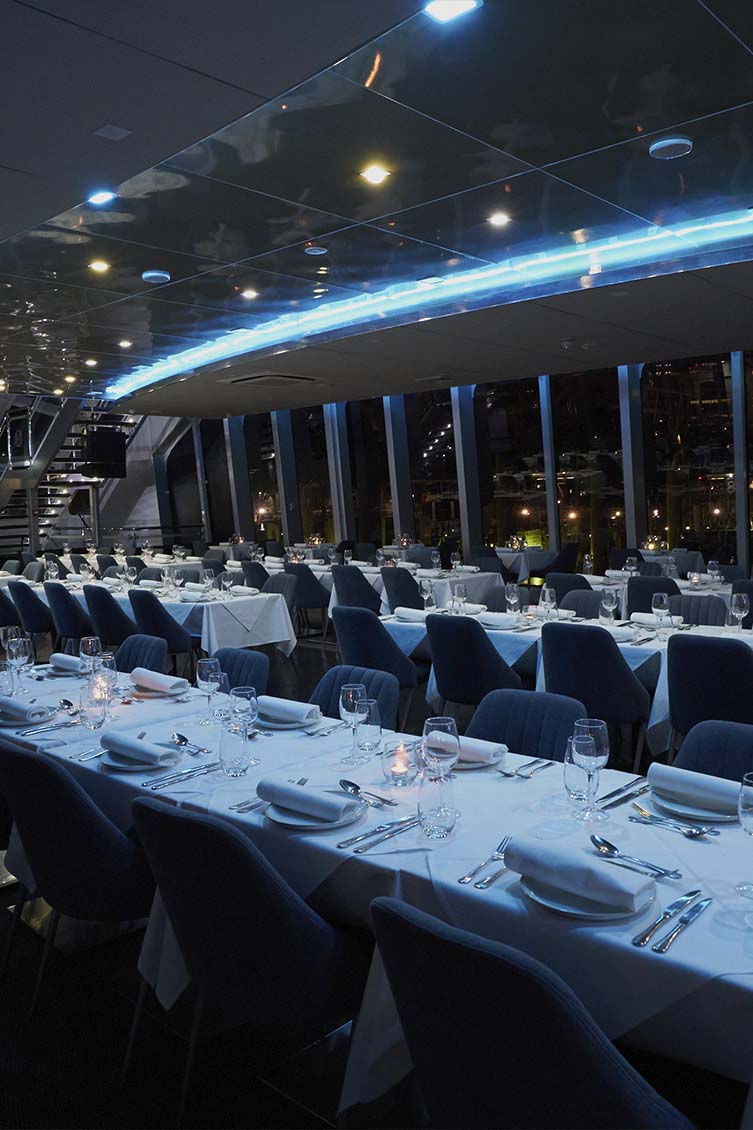 The main dining deck of the Clearview Glass Boat with floor-to-ceiling windows and ambient lighting