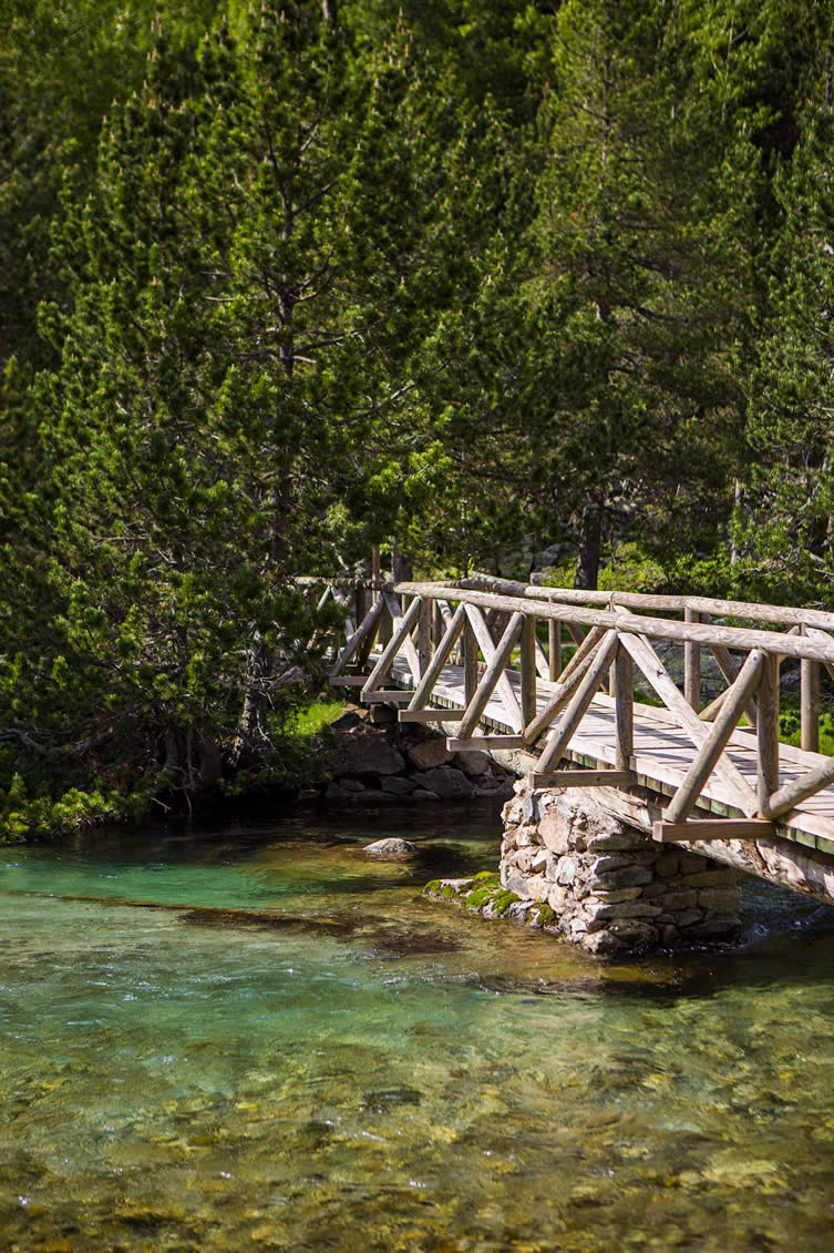 A bridge spans on of the crystal clear alpine rivers in the Parc Nacional d'Aigüestortes i Estany de Sant Maurici